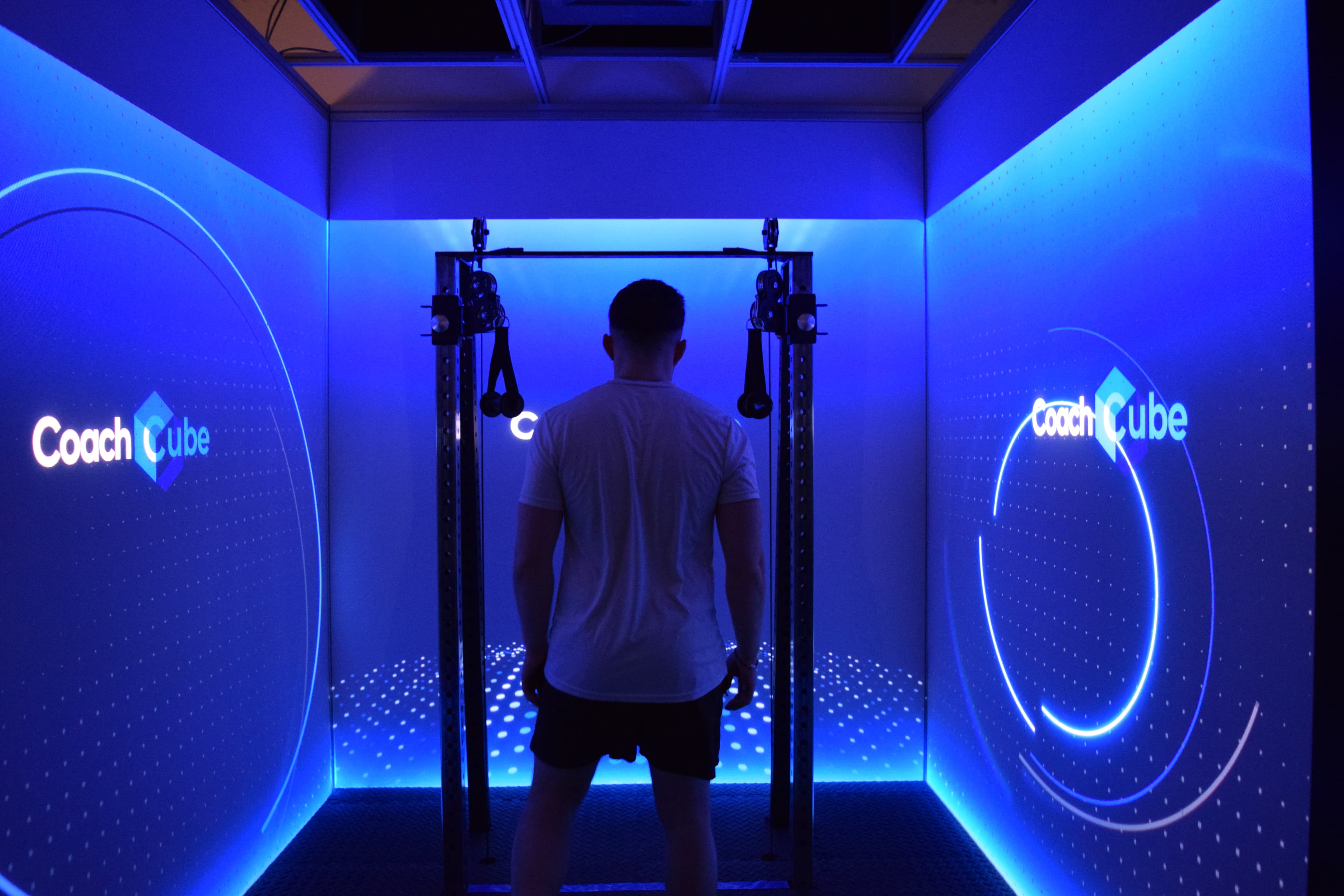 Inside the CoachCube — blue projection screens and gym rig